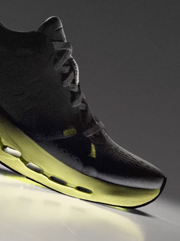 Grey sneaker with yellow sole on a dark background