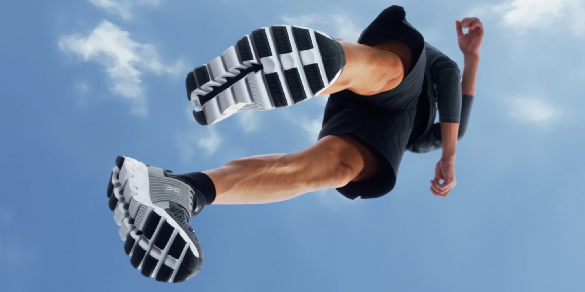 Person running with black and white shoes against a blue sky