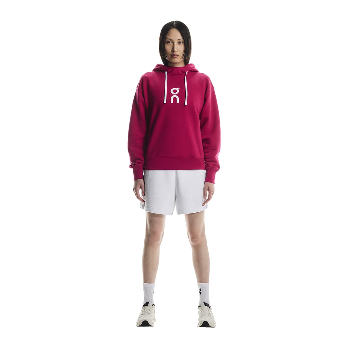 Full-body of female model wearing the On Apparel - Club Hoodie Colour Grenadine
