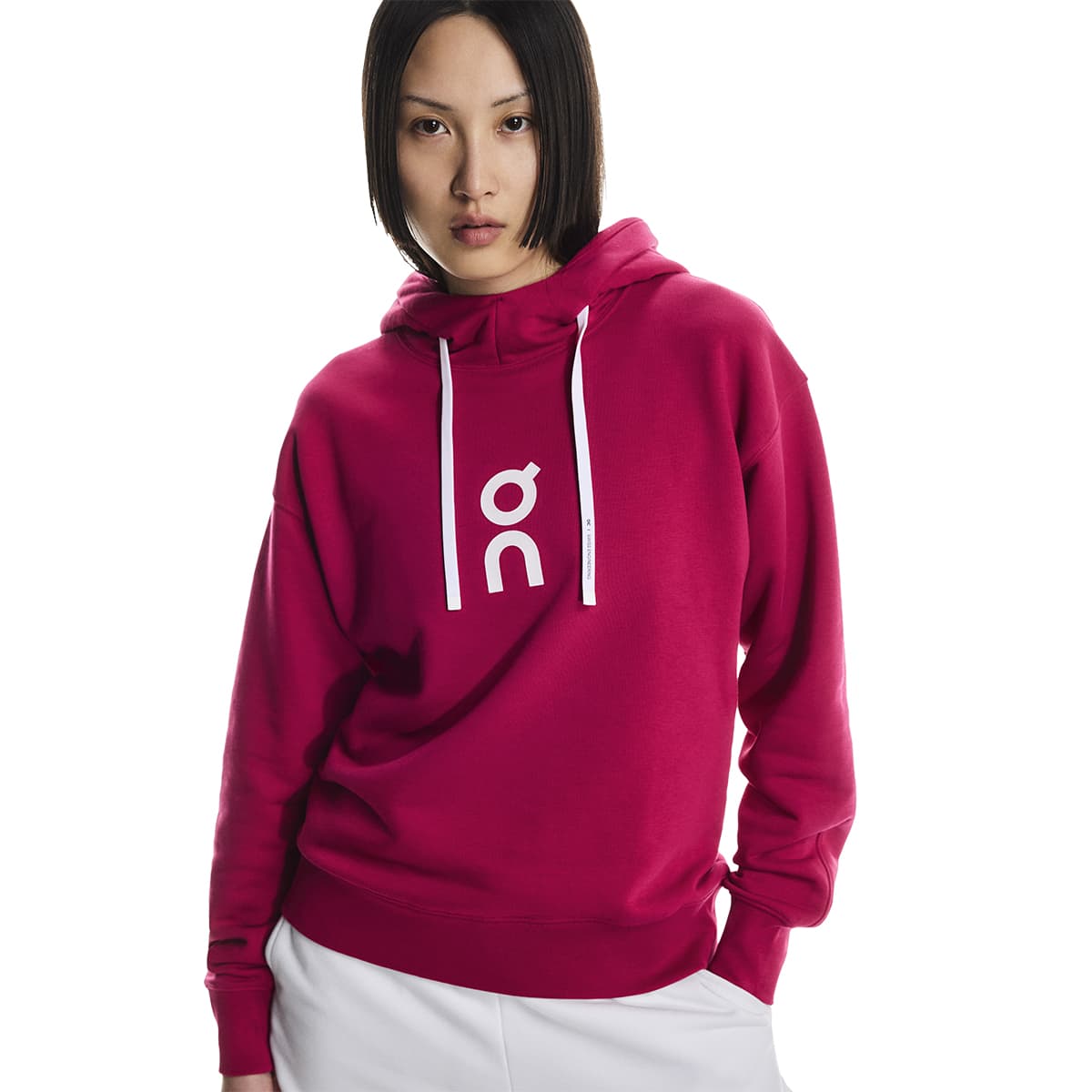Female model wearing the On Apparel - Club Hoodie Colour Grenadine in a relaxed pose