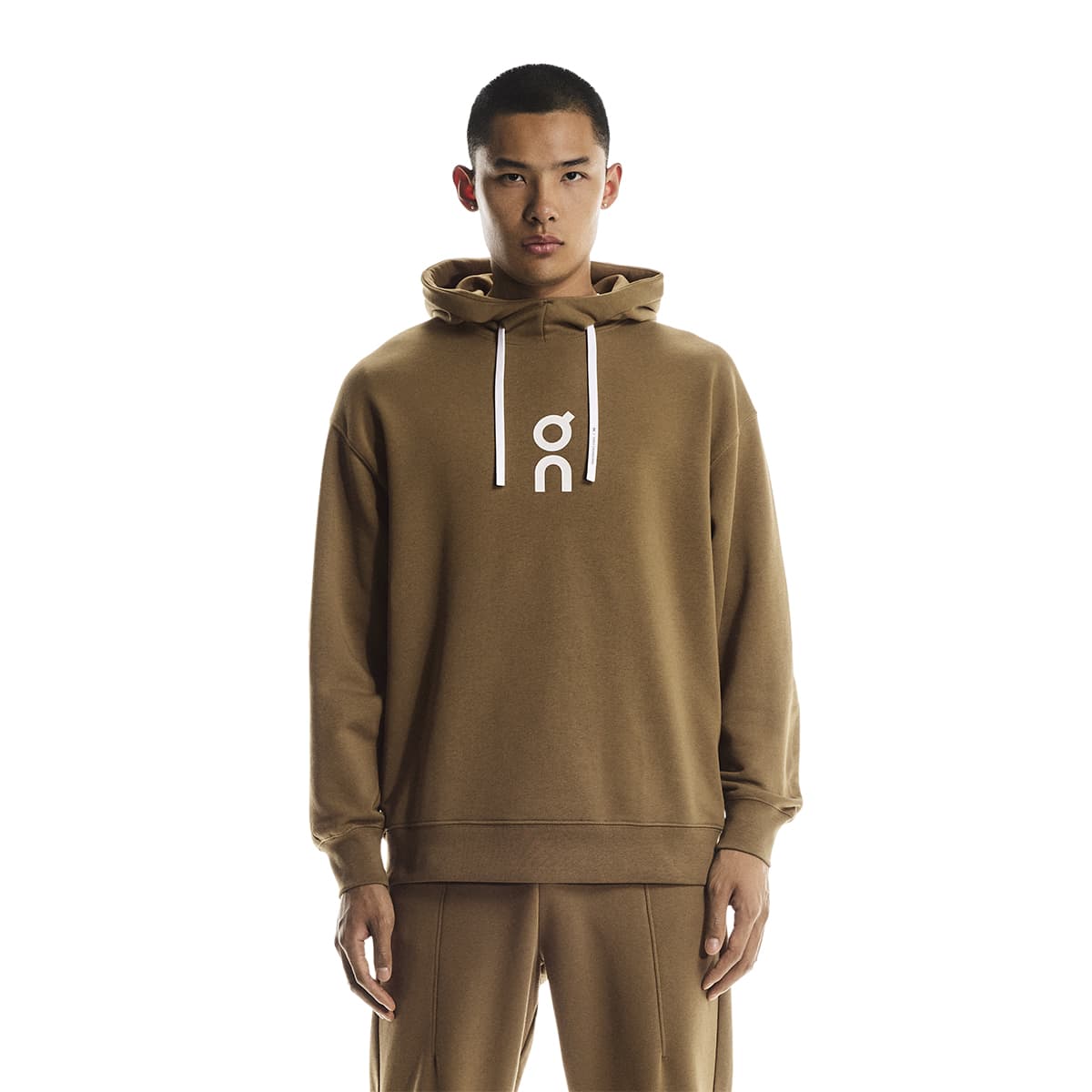 Male model front view of the On Club Hoodie in Nutmeg with hood down and hands at sides