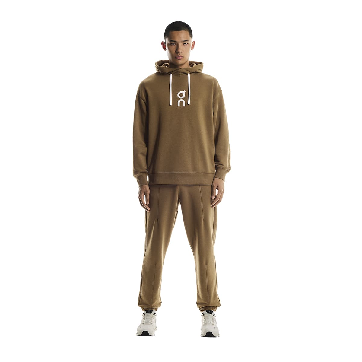 Full front view of male model wearing the On Club Hoodie in Nutmeg with matching track pants
