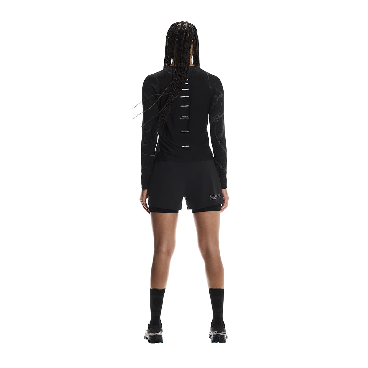 Female model wearing the On Apparel - Performance Long T Lumos Colour Black in a dynamic pose