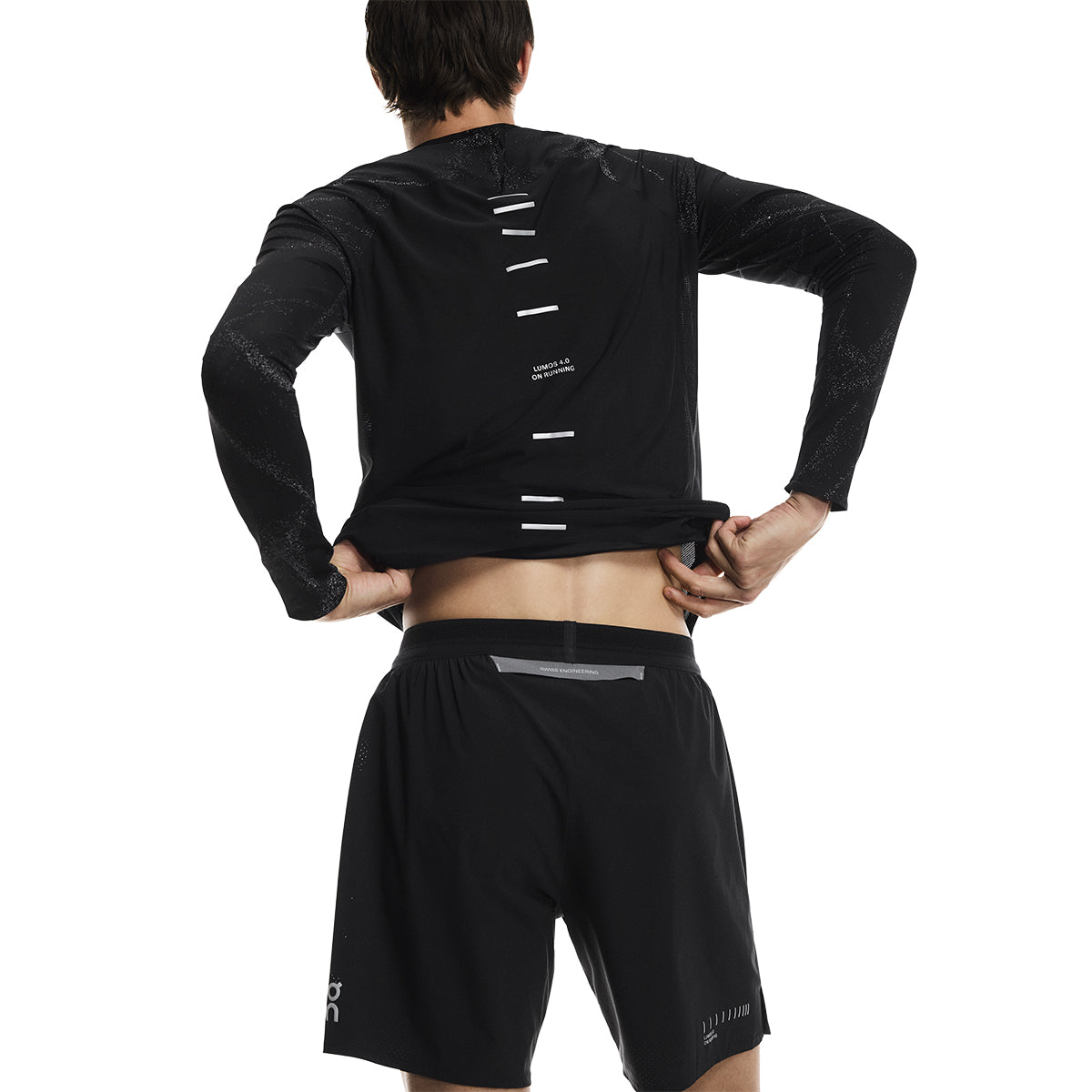 Rear view of male model lifting shirt to show waistband of the On Performance Shorts Lumos in Black