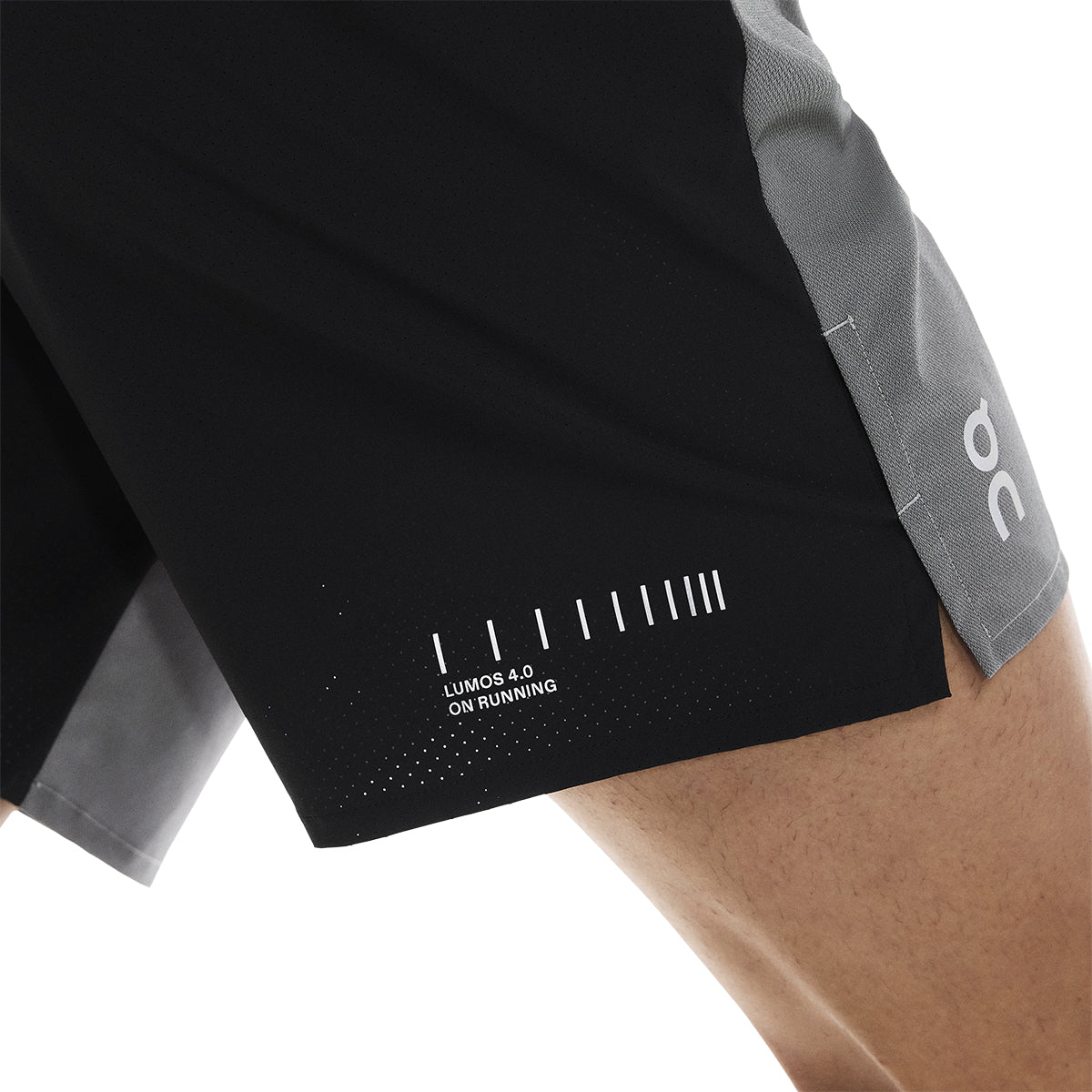 Detail of side hem on the On Performance Shorts Lumos in Black showing Lumos print and perforation