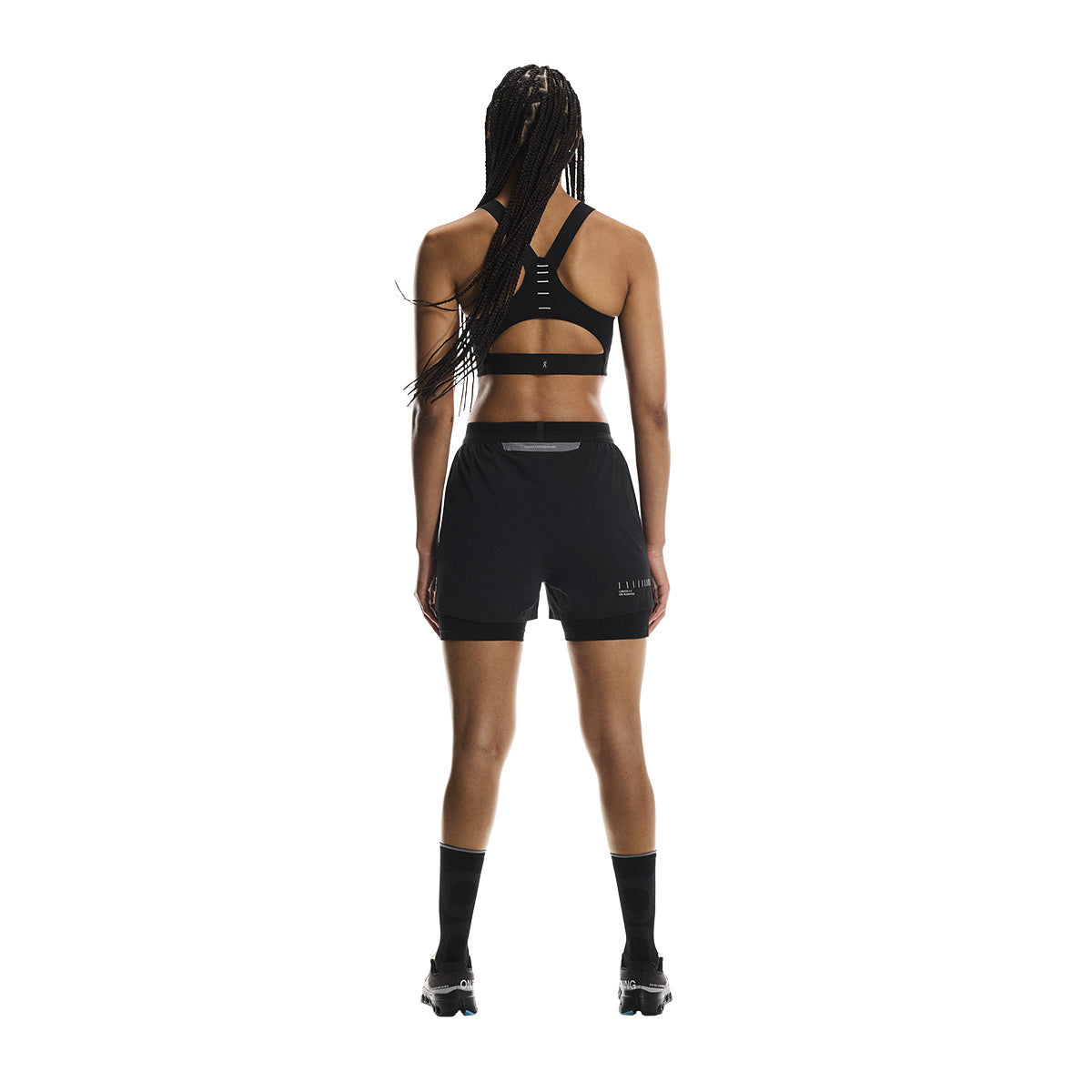 Full back view of female model wearing the On Performance Shorts Lumos in Black