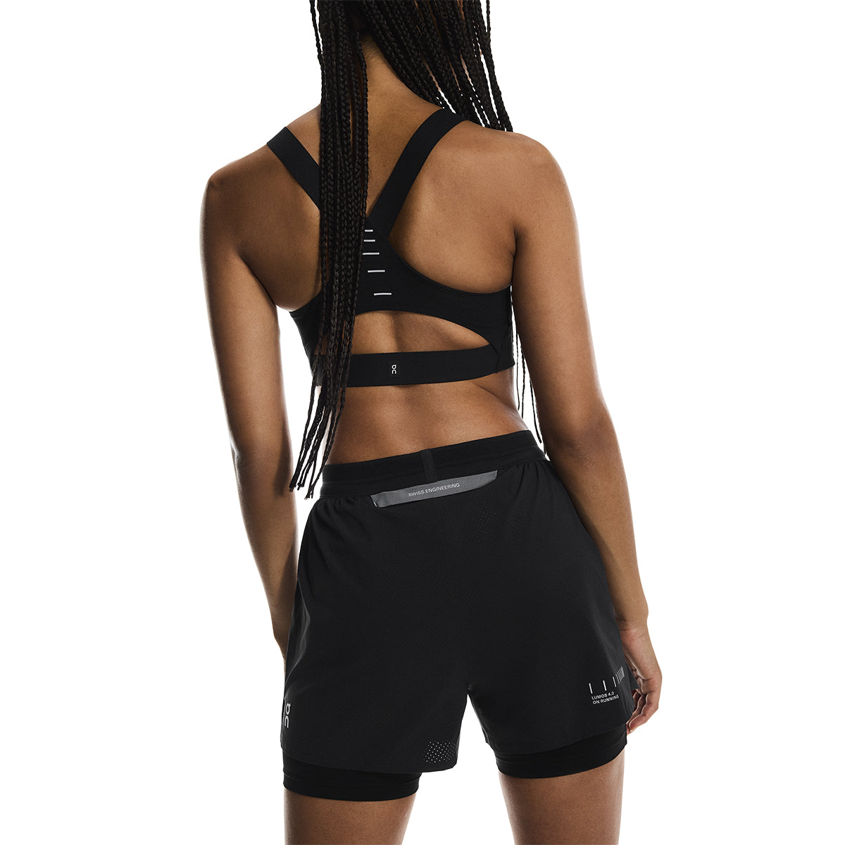 Angled back view of female model in the On Performance Shorts Lumos in Black