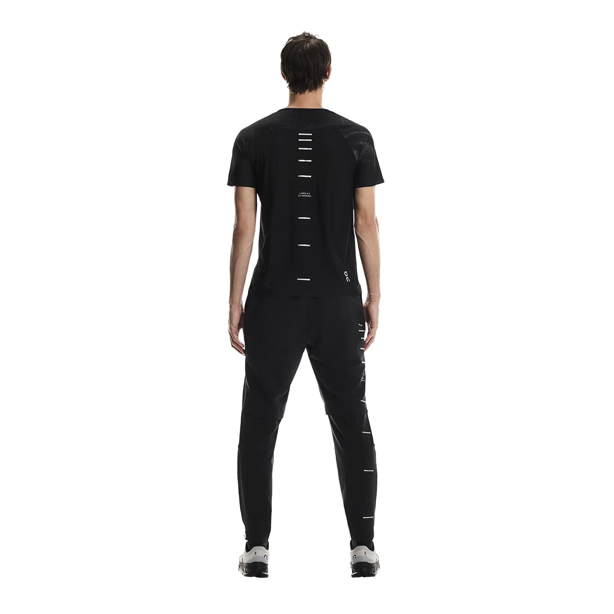 Full back view of male model in the On Weather Pants Lumos in Black with reflective stripes visible