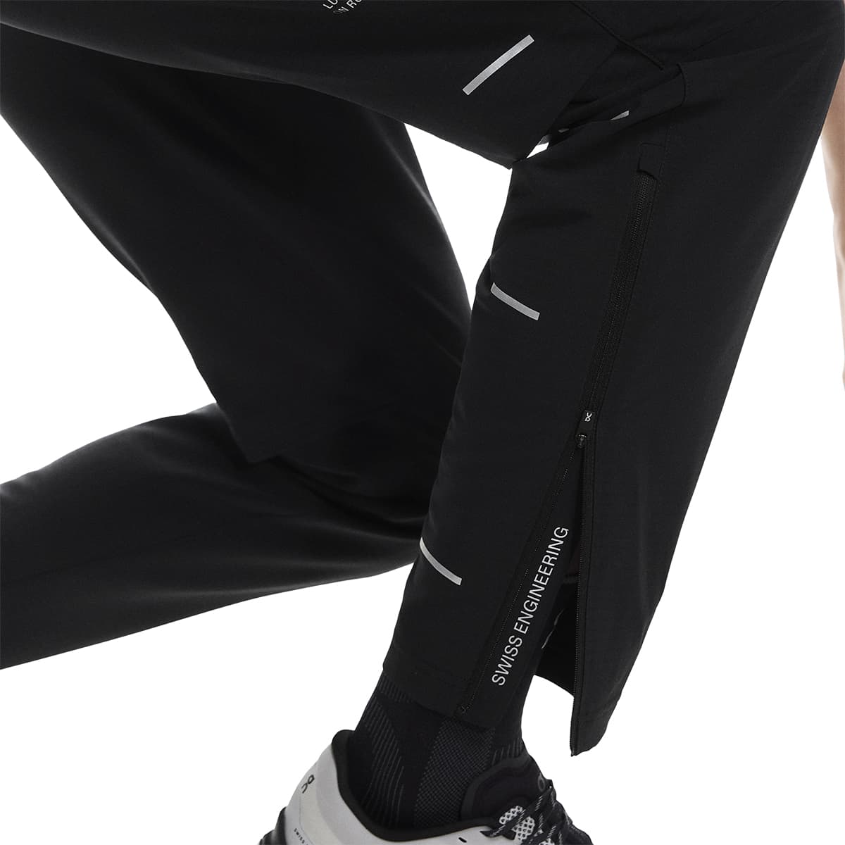 Side leg view of the On Weather Pants Lumos in Black showing ankle zips and “Swiss Engineering” print