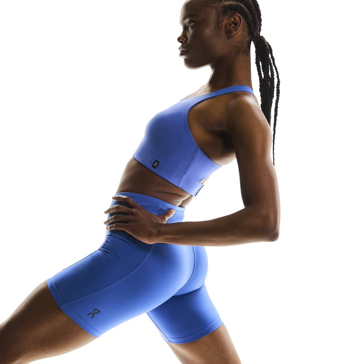 Side view of female model stretching in the On Performance Short Tights in Zaffre