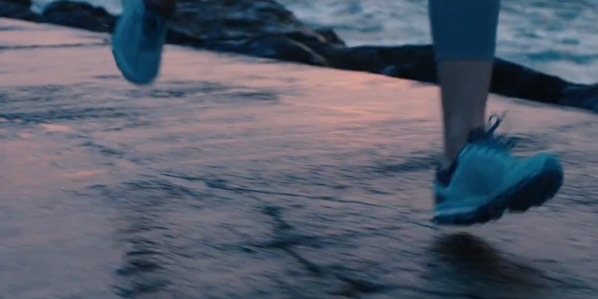 Person running on a reflective water surface with blue shoes.