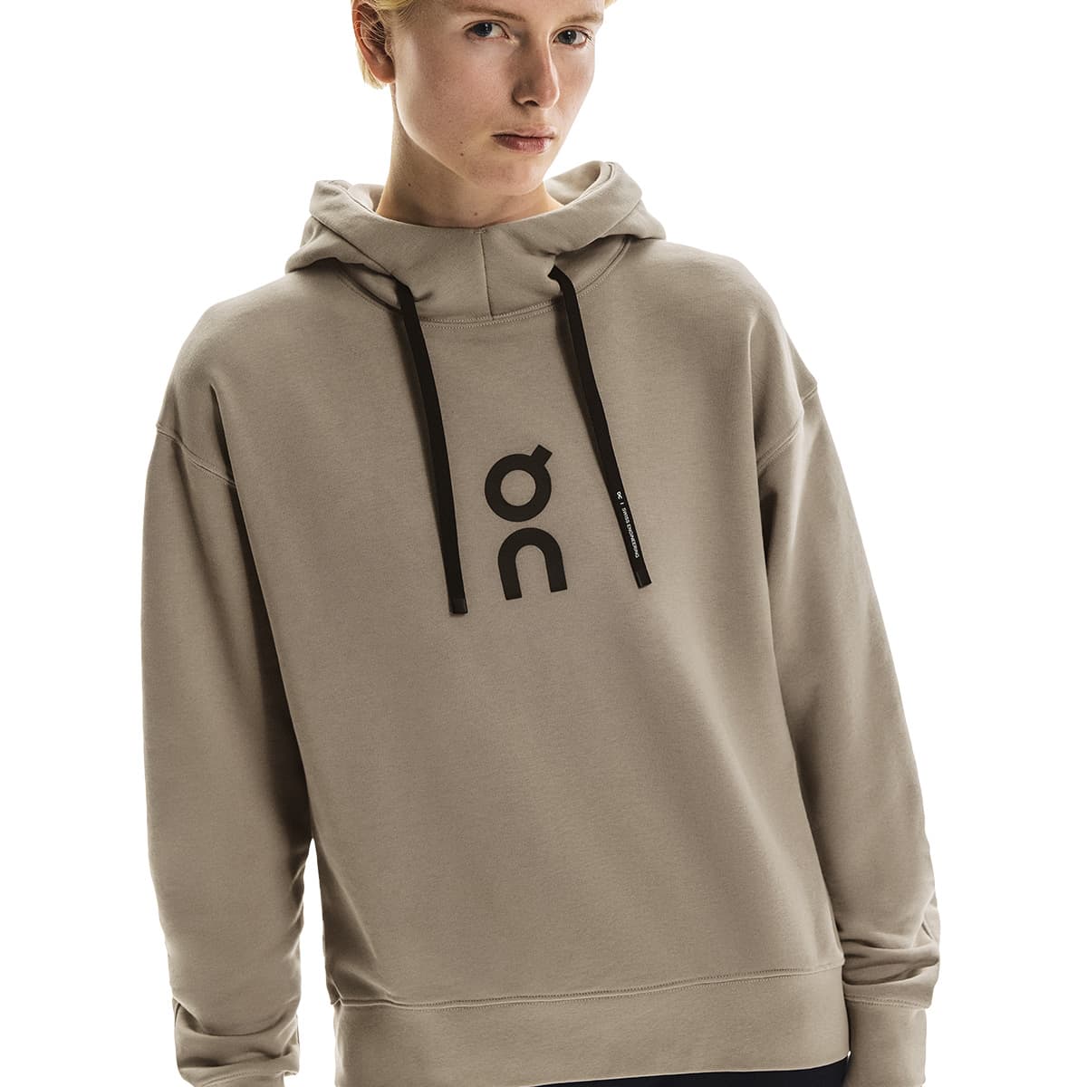 Close-up of female model in the On Club Hoodie in Desert showing logo and hood detail