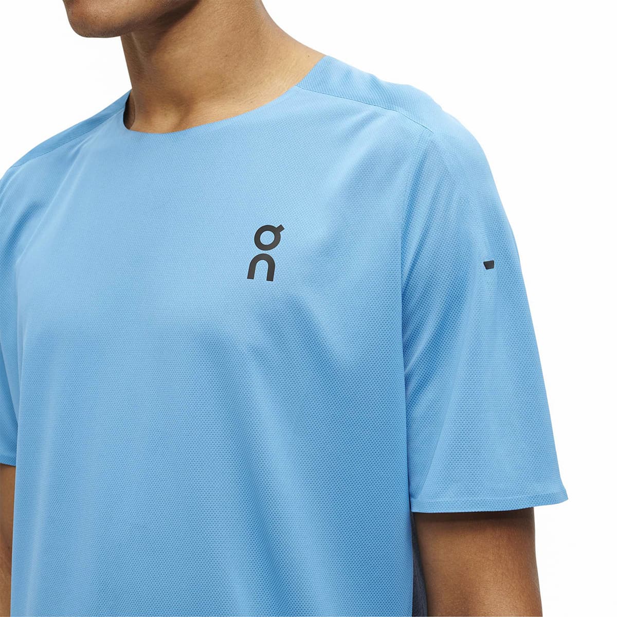 Man wearing the On Performance T Colour Niagra-Navy - Front Close Up Logo