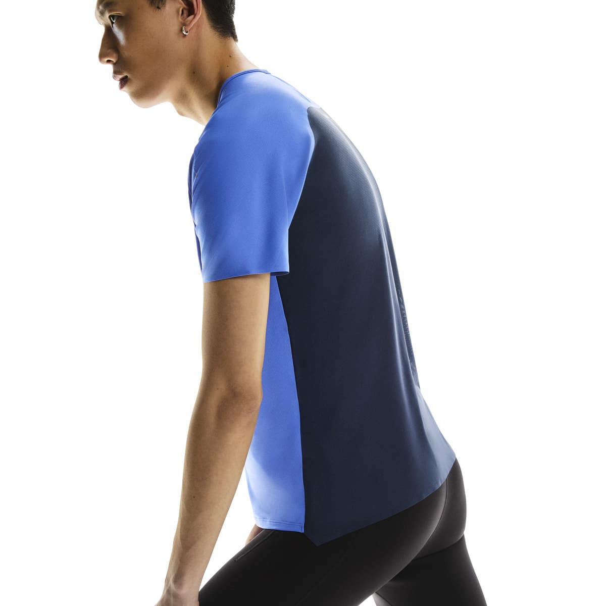 Side profile of male model stretching in the On Performance T in Zaffre Navy