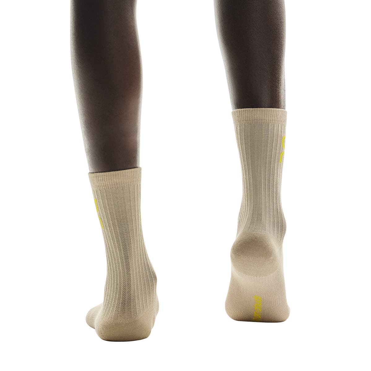 Rear view of model wearing the beige pair from the On Logo Sock 3-Pack in Desert Wash #color_desert-wash