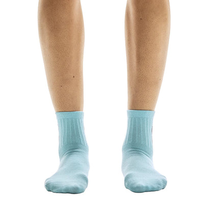 Front view of model wearing the blue pair from the On Logo Sock Mid 3-Pack in Desert Wash 