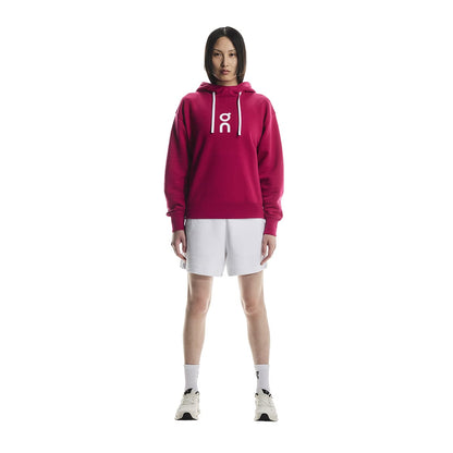 Full-body of female model wearing the On Apparel - Club Hoodie Colour Grenadine 