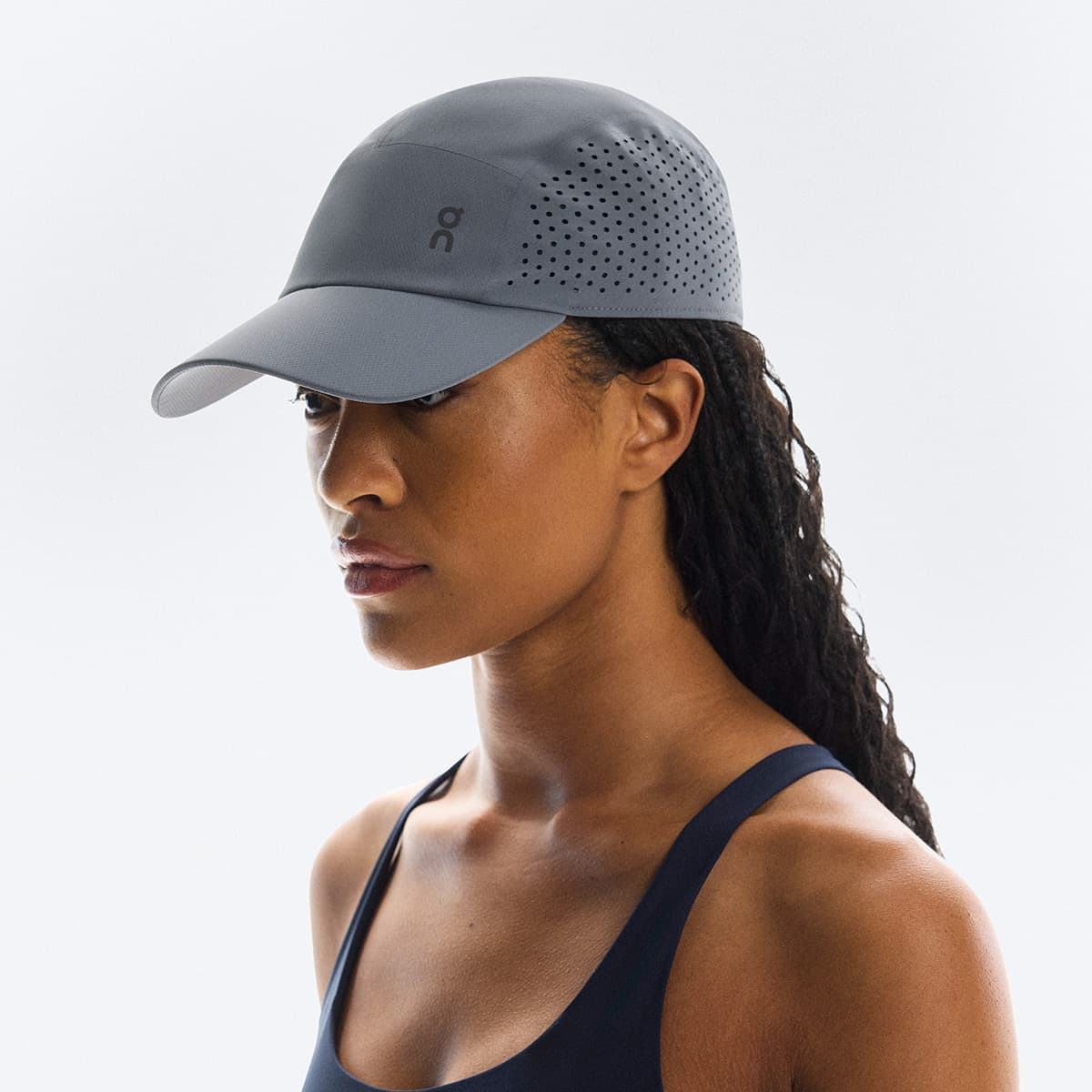 Front angled view of female model wearing the On Lightweight Cap in Rock #color_rock