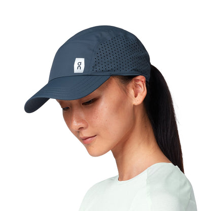 Female Model wearing the On Lightweight Cap Colour navy - Close up peak logo 